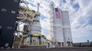 Ozinga slag grinding mill, metal piping and yellow platforms, with an American flag flying beside the structures.