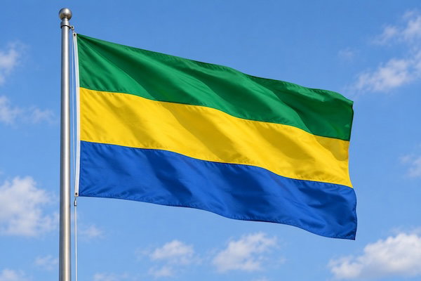 Gabonese flag flying on a flagpole against a blue sky.
